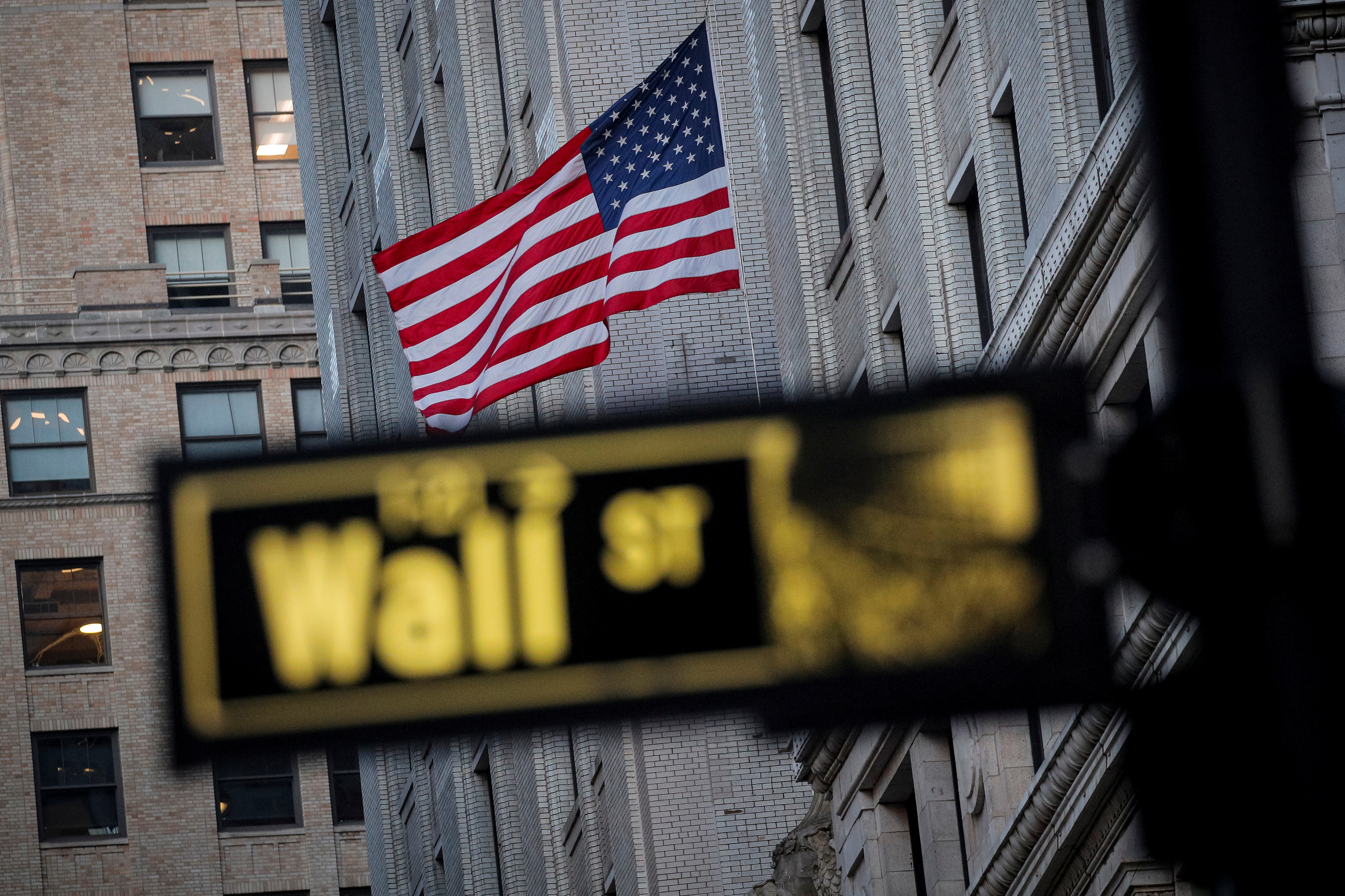 wall street sign can be seen in front of a US flag