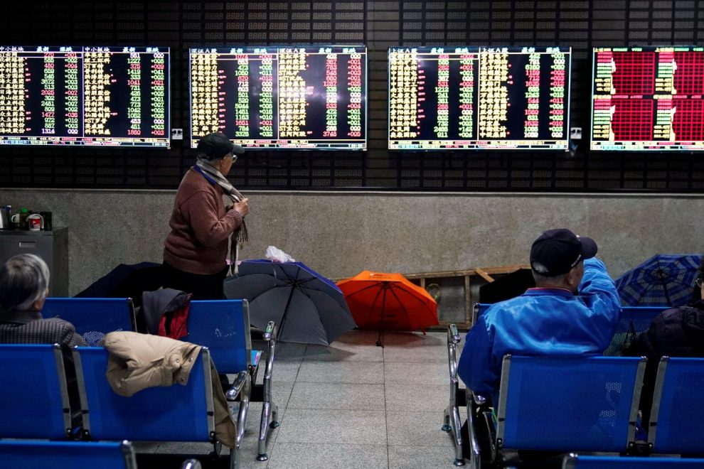 Traders looks at prices of China stocks from market indicator boards.