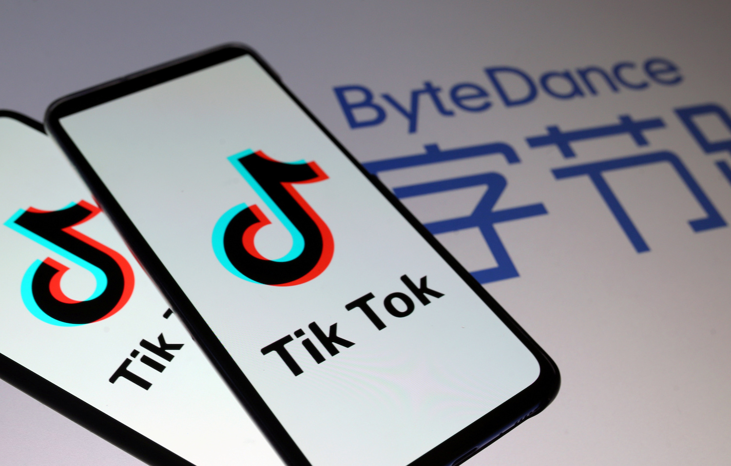 Tik Tok logos are seen on smartphones in front of a displayed ByteDance logo in this illustration