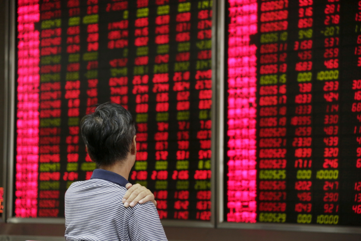 An investor looks at an electronic board at a brokerage house in Beijing