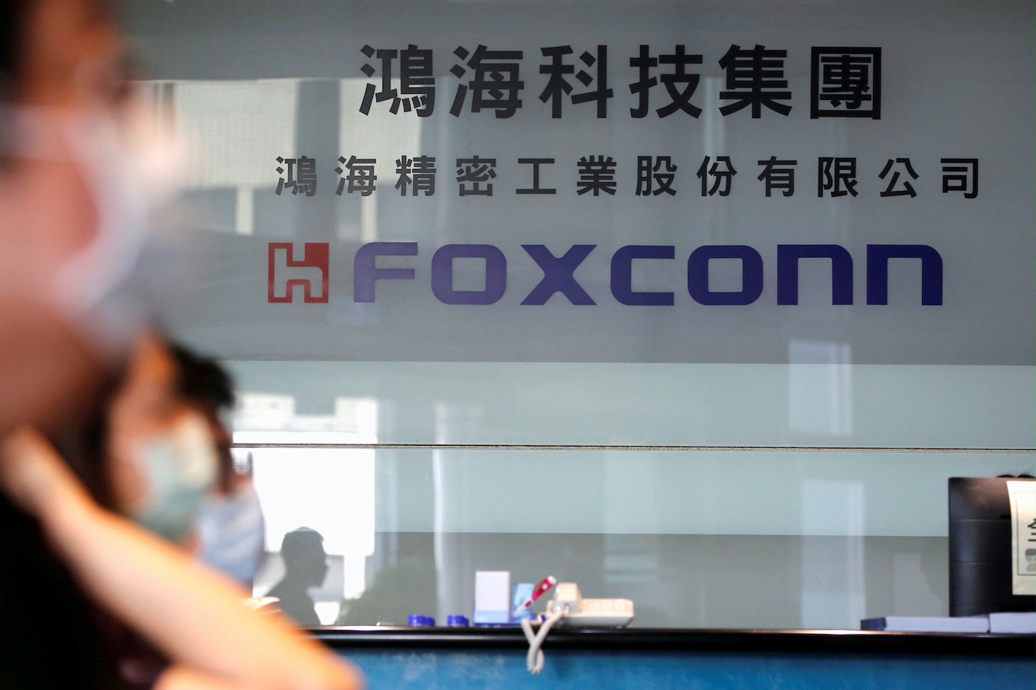 People wear masks to protect themselves from coronavirus disease (COVID-19) while listening to the annual general meeting at the lobby of Foxconn's office in Taipei