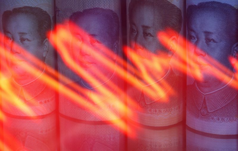 Chinese Yuan banknotes are seen behind illuminated stock graph in this illustration