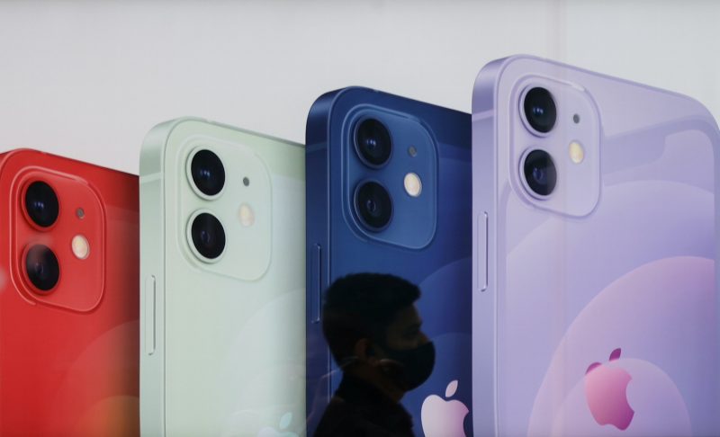 A salesperson walks past an advertisement at an Apple reseller store