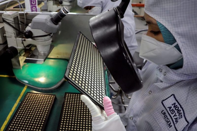 A worker inspects chips at the semiconductor packaging firm Unisem (M) Berhad plant in Ipoh