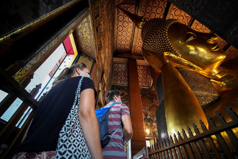 Foreign tourists are seen next to the Reclining Buddha at Wat Pho,