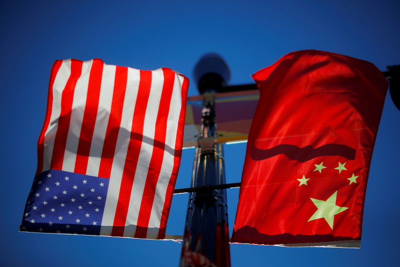 The flags of the United States and China fly from a lamppost in Boston