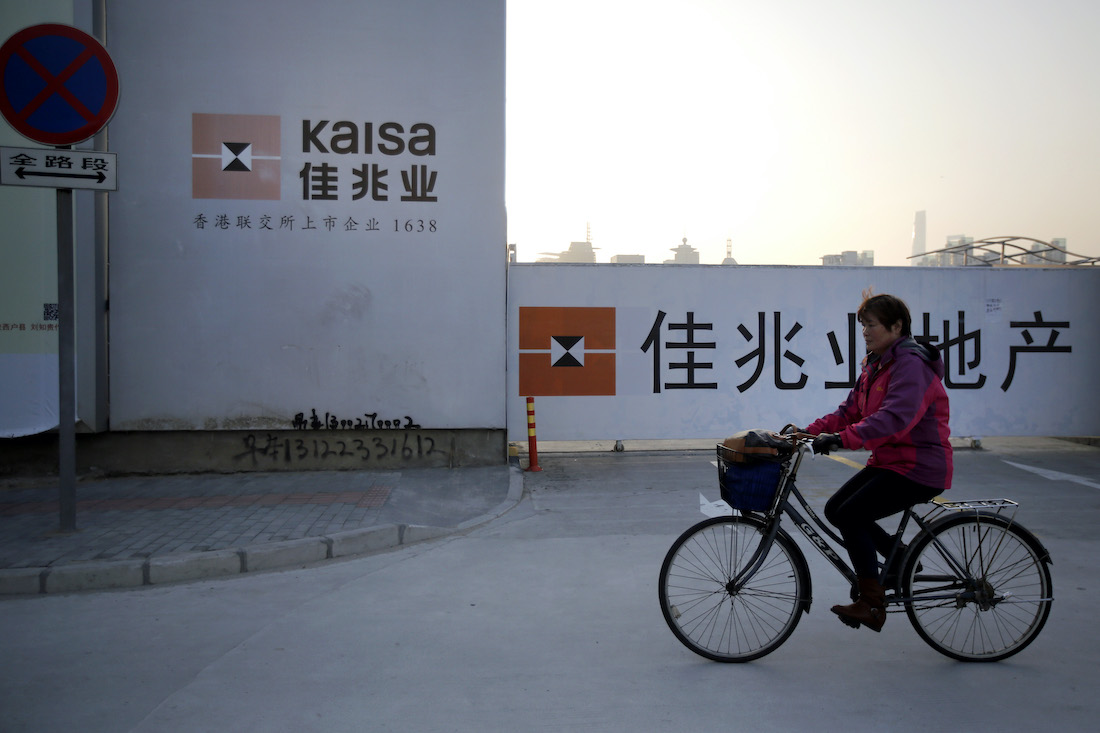 A woman rides her bike bChinese property developer Kaisa Group