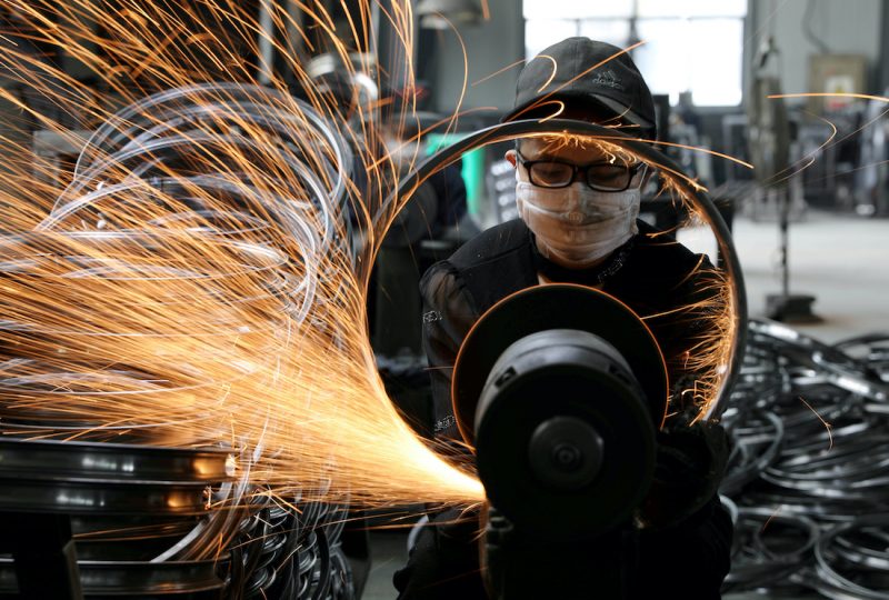 Worker welds a bicycle steel rim at a factory manufacturing sports equipment in Hangzhou, Zhejiang