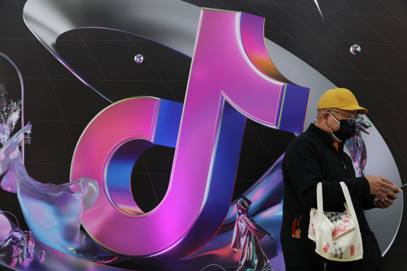 Man stands near a giant sign of Chinese company ByteDance's app TikTok, known locally as Douyin, during China Fashion Week, in Beijing