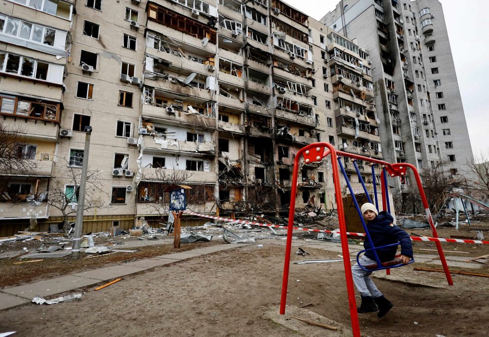 A child sits on a swing in front of a damaged residential building in Kyiv, Ukraine February 25, 2022. Blasts were heard before dawn on Monday in the capital Kyiv and in the northeastern city of Kharkiv, Ukrainian authorities said. But Russian ground forces' attempts to capture major urban centres had been repelled, they added. Reuters Image