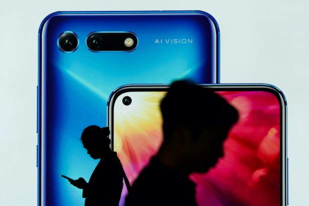 People walk past an ad for Huawei smartphones at an airport in Shenzhen, China