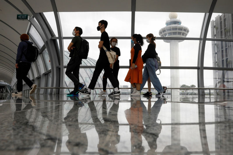 People pass the control tower of Singapore's Changi Airport