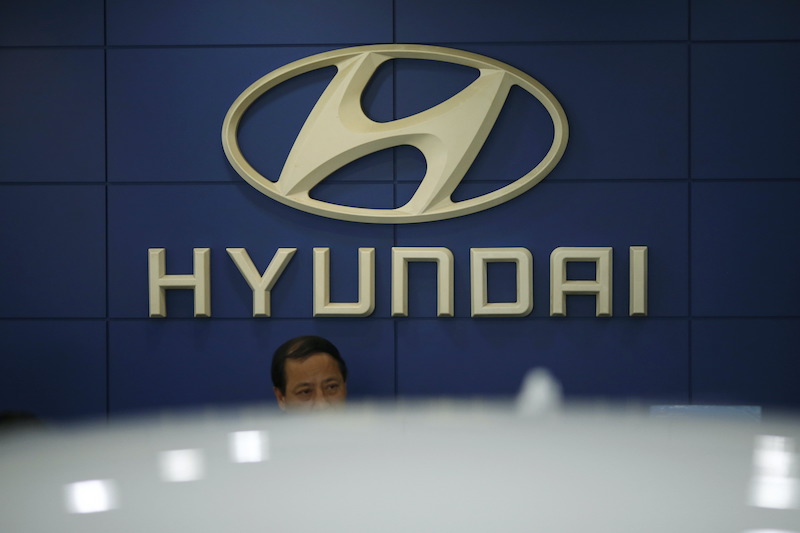 An employee sits in front of the logo of Hyundai Motor at its dealership in Seoul