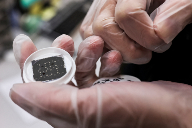 An engineer holds a chip while posing for a photo