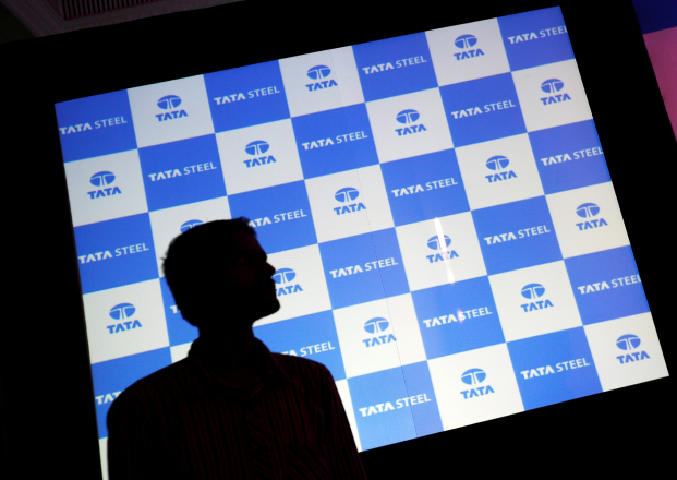A man walks past a screen displaying Tata Steel logo