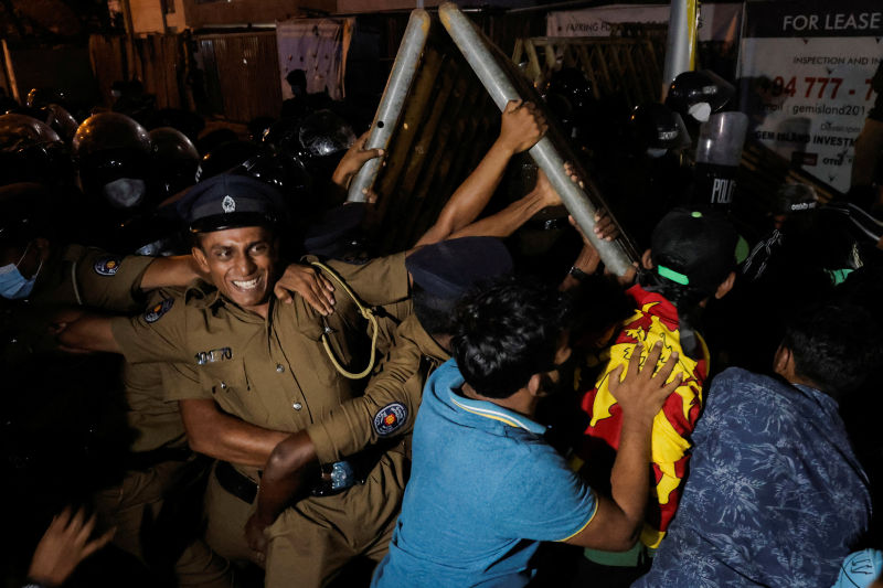 Sri Lanka police hold metal barrier gates in place