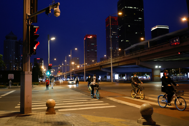 People wearing masks ride shared bicycles in Beijing during its Covid lockdown.