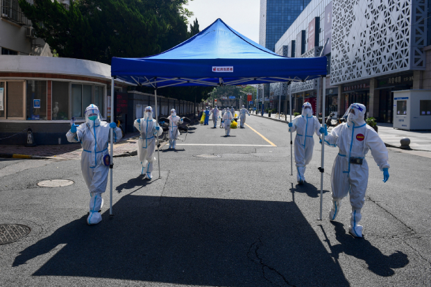 Workers in protective suits move equipment