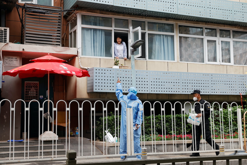 A resident talks to a worker in a protective suit at a residential building under lockdown in Beijing on June 13, 2022.