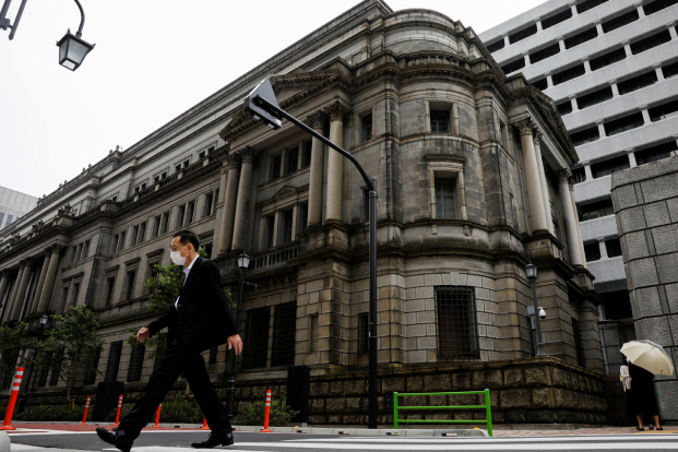 A man wearing a protective mask walks past the headquarters of Bank of Japan