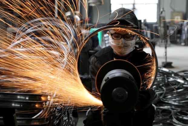 Worker polishes a bicycle steel rim at a factory manufacturing sports equipment in Hangzhou, Zhejiang