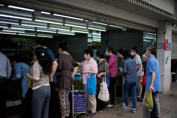 People wearing face masks line up at a food store in Shanghai after the end of the Covid lockdown.