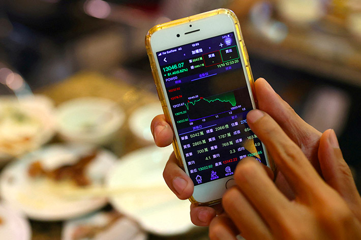 A person displays stock data on his phone in a restaurant in Taipei, Taiwan