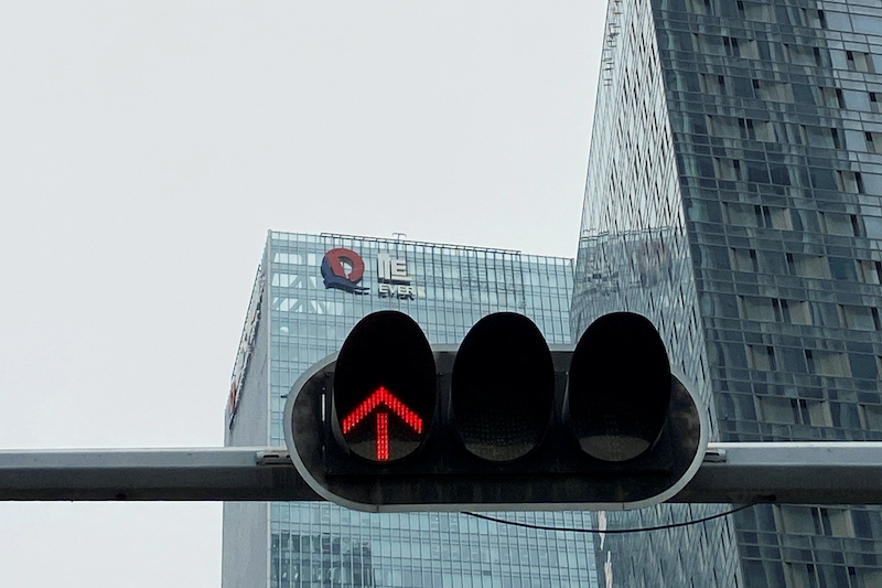 A partially removed company logo of China Evergrande Group is seen on the facade of its headquarters, near a traffic light in Shenzhen, Guangdong province, China