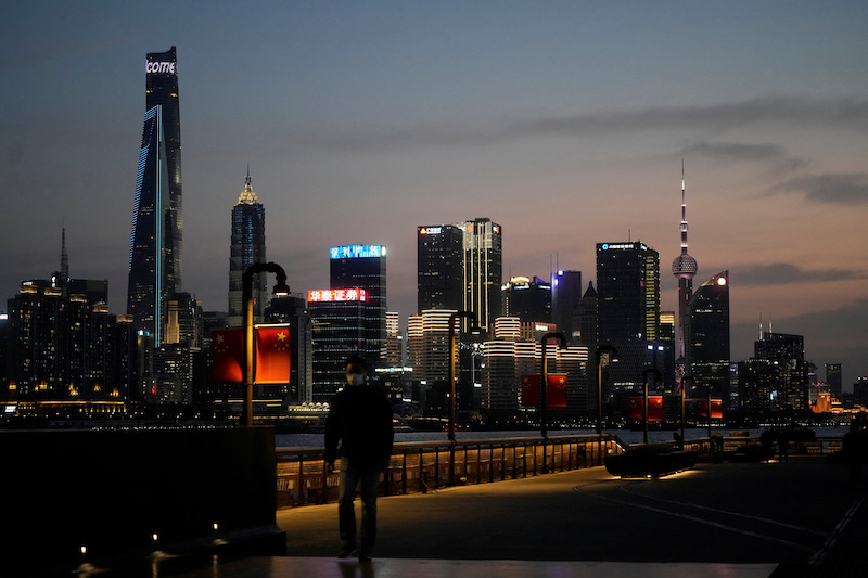 a man walking in front of Lujiazui financial district across the Huangpu river at dusk in Shanghai, amid the Covid lockdown on March 28, 2022