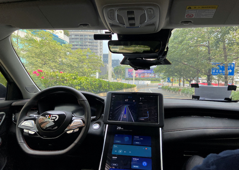 A safety driver sits on the passenger seat as a smart car with an autonomous driving system drives along a street in Shenzhen, China