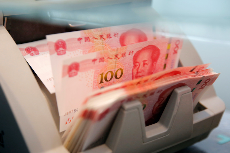 2016 年 3 月 30 日，中国北京一家商业银行的分行，一名工作人员在点钞机上点钞机上的 100 元人民币钞票。路透社/Kim Kyung-Hoon/档案照片