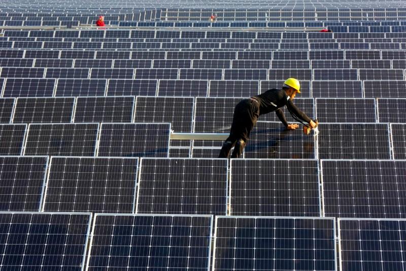A man works on solar panels at a solar power plant of China Huaneng Group in Huaiyin, Jiangsu province, China