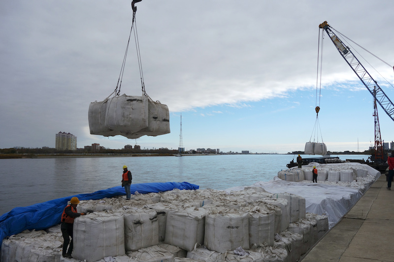 Workers stand near a crane unloading sacks of imported soybeans from Russia at Heihe port in Heilongjiang province, China on October 10, 2018