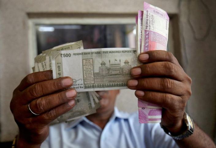 A cashier checks Indian rupee notes