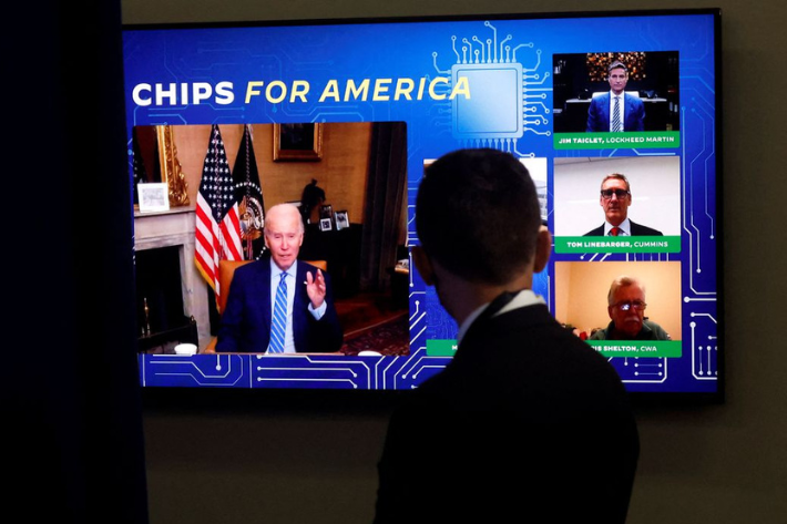A White House press aide looks on as US President Joe Biden appears virtually in a meeting with business and labor leaders about the Chips Act in an auditorium on the White House campus in Washington, US