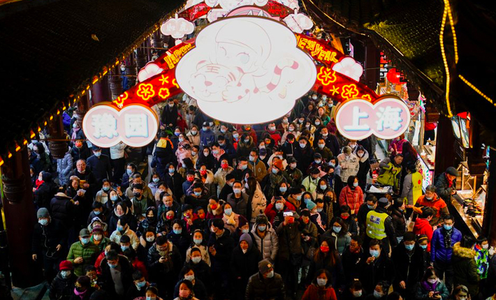 People wearing protective masks walk by an area decorated with lanterns during the Chinese Lunar New Year festivity at Yu Garden, following new coronavirus disease (COVID-19) cases in Shanghai, China