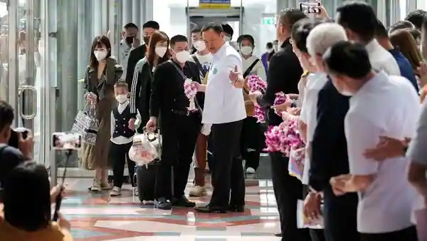 Thai health minister Anutin Charnvirakul, centre in white shirt, handles out orchid necklaces to Chinese tourists who arrived at Bangkok airport on Monday January 9, 2023.