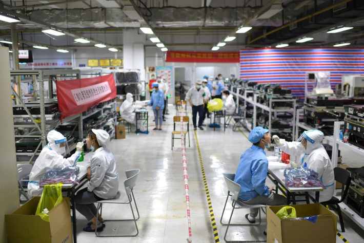 Medical workers in protective suits collect swabs from workers for nucleic acid testing at a Foxconn factory, following new cases of the coronavirus disease (COVID-19) in Wuhan, Hubei province, China