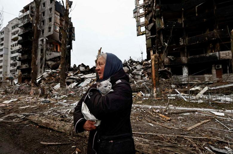 An elderly woman holds a pet amid a battered landscape in Ukraine. The US announced further sanctions on companies alleged to be backing Russia's war effort, while it and other countries also announced more military aid on Friday.