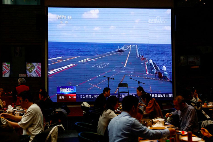 Customers dine near a giant screen broadcasting news footage of an aircraft taking off from China's Shandong aircraft carrier while taking part in a combat readiness patrol and "Joint Sword" war exercises around Taiwan conducted by the Eastern Theatre Command of China's People's Liberation Army (PLA), at a restaurant in Beijing, China
