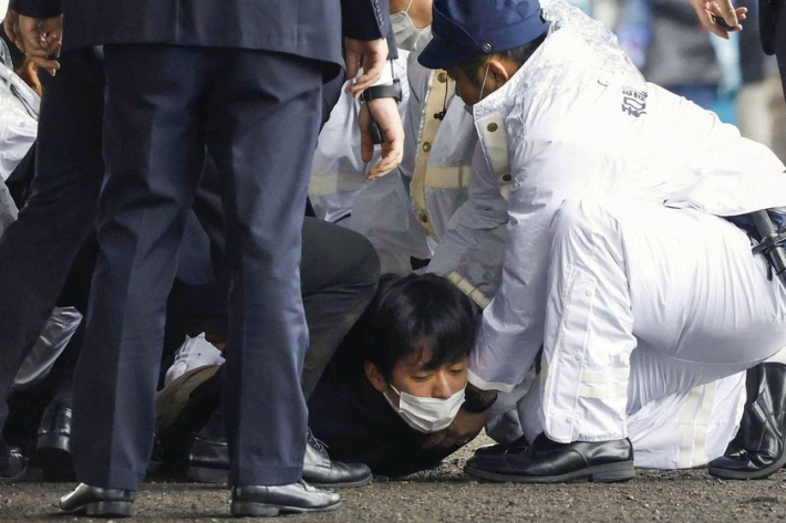 A man, believed to be a suspect who threw a pipe-like object near Japanese Prime Minister Fumio Kishida during his outdoor speech, is held by police officers at Saikazaki fishing port in Wakayama, south-western Japan
