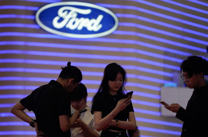 People stand near a logo of Ford at the Auto Shanghai show, in Shanghai, China April 18, 2023. REUTERS/Aly Song