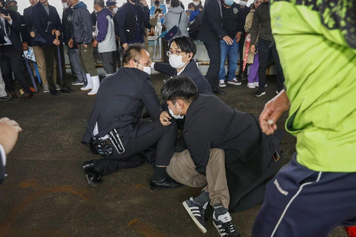 A man, believed to be a suspect who threw a pipe-like object near Japanese Prime Minister Fumio Kishida during his outdoor speech, is held by police officers at Saikazaki fishing port in Wakayama, south-western Japan