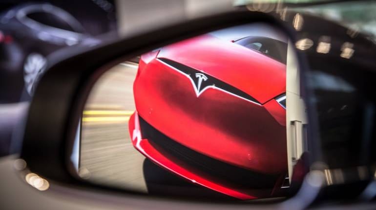 Tesla symbol is seen in a rear-view mirror.