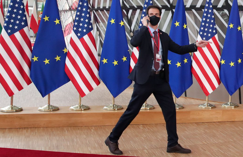 A security guard walks near EU and U.S. flags, before the EU-US summit, in Brussels, Belgium June 15, 2021. REUTERS/Yves Herman