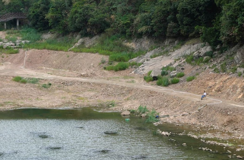 A man draws water with a pump on a dried-up reservoir amid hot temperatures, while many regions from southwest to east of the country along the Yangtze river have been experiencing weeks of record-breaking heatwave in Changxing, Zhejiang province, China, August 20, 2022. REUTERS/Aly Song