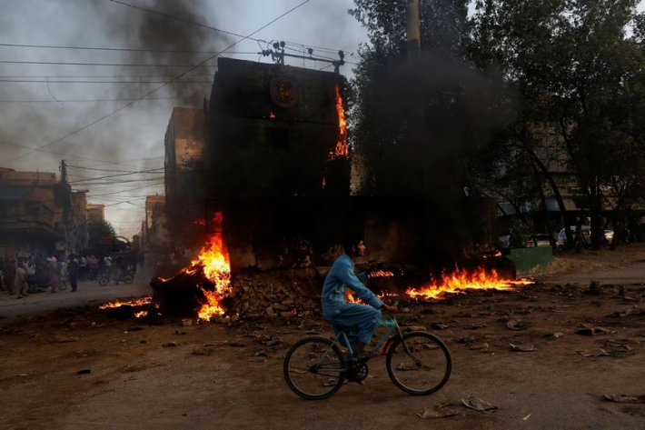 A boy rides past a paramilitary check post, that was set afire by the supporters of Pakistan's former Prime Minister Imran Khan, during a protest against his arrest, in Karachi, Pakistan