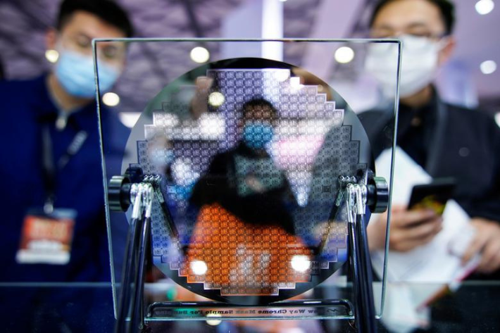 Visitors look at a display of a semiconductor device at Semicon China, a trade fair for semiconductor technology, in Shanghai, China