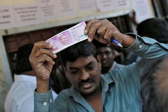 A man holds 2000 Indian rupee notes as he leaves a bank in Mumbai, India