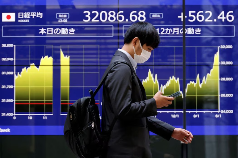 A man walks past an electric monitor displaying Japan's Nikkei share average and recent movements, outside a bank in Tokyo, Japan, June 5, 2023. REUTERS/Issei Kato